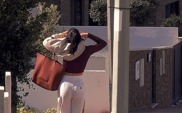 Mujer en pantalones blancos quitándose la blusa en la calle - Foto, Imagen