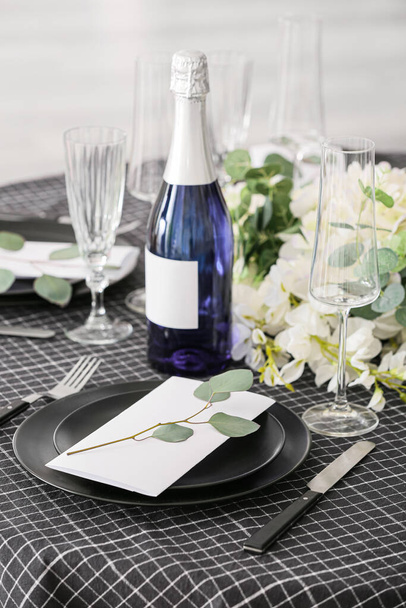 結婚式の招待状とシャンパンのボトルとスタイリッシュなテーブルセッティング - 写真・画像