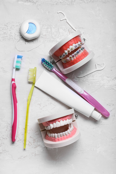 Modelo de mandíbulas com aparelho, escovas de dentes, pasta e fio dental sobre fundo claro - Foto, Imagem