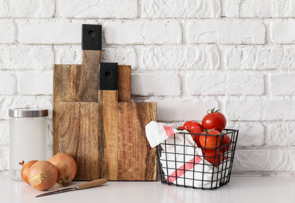 Wooden cutting boards and fresh vegetables on table near white brick wall - Photo, Image