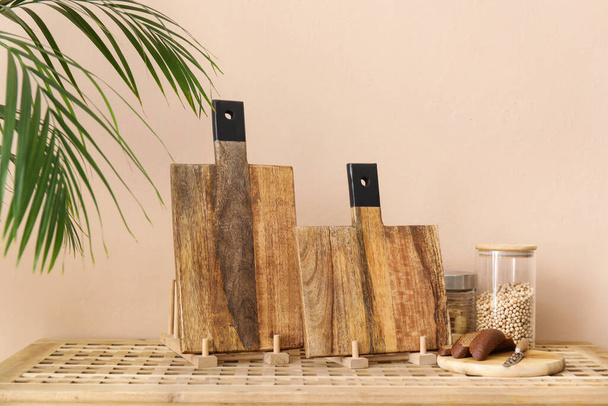 Wooden cutting boards, bread and jars with products on table near light wall - Photo, Image