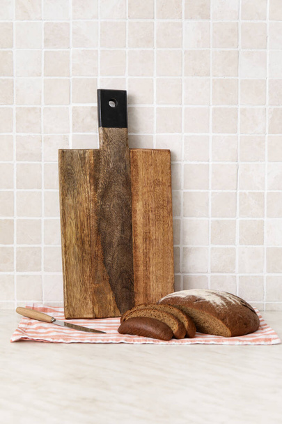 Wooden cutting boards and bread on table near tile wall - Fotografie, Obrázek