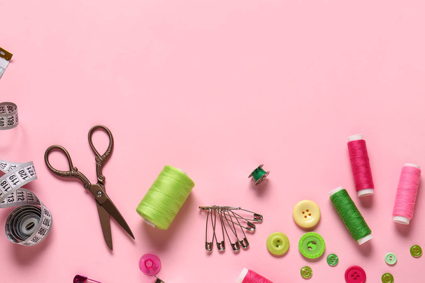 Bobine di filo, forbici, spilli di sicurezza e bottoni su sfondo rosa - Foto, immagini