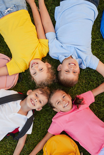 Happy schoolchildren lying on lawn - Φωτογραφία, εικόνα
