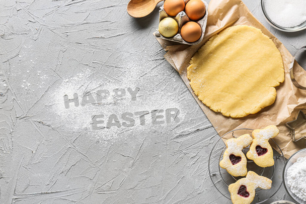 Fresh dough for preparing cookies and text HAPPY EASTER on grey background - Photo, Image