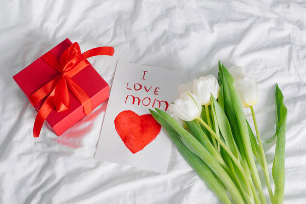 Τουλίπες λουλούδια, κόκκινο κουτί δώρου και κάρτα με κείμενο αγαπώ μαμά. Έννοια της ημέρας των γυναικών, ημέρα των μητέρων. Άνω όψη - Φωτογραφία, εικόνα