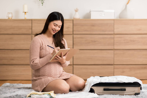 Asian pregnant woman preparing diaper, feeding bottle for baby at home. Pregnant woman packing baby stuff ready for the maternity hospital. Pregnancy Prepare for Newborn Concept - Foto, Imagem