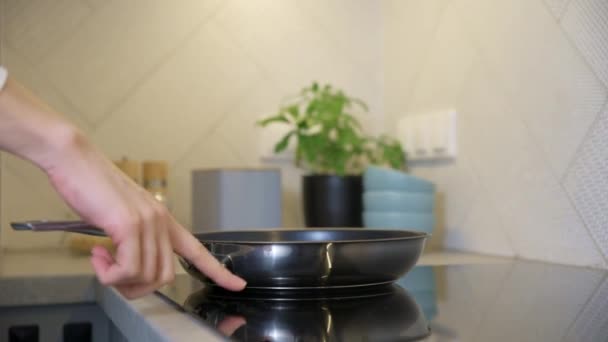Γυναίκα ενεργοποιήσετε το κουμπί στην επαγωγική σόμπα με τηγάνι χάλυβα στην κουζίνα, Σύγχρονη συσκευή κουζίνας - Πλάνα, βίντεο