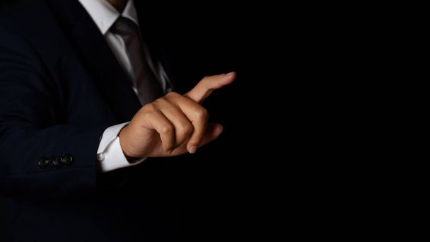 Young businessman pointing finger touching on screen black background. copy space. - Foto, afbeelding