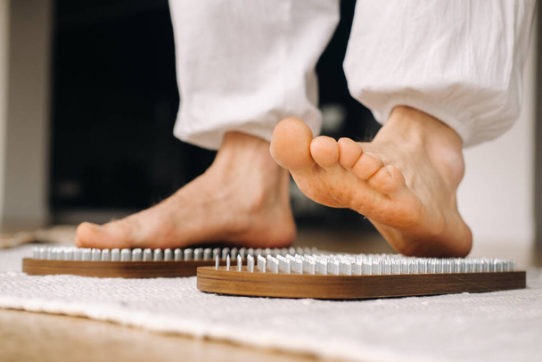 The man's feet are next to boards with nails. Yoga classes. - Foto, imagen