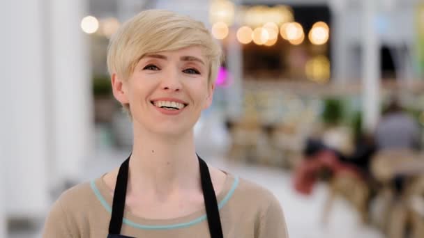 Kypsä aikuinen keski-ikäinen 40-vuotias nainen nainen ravintola kahvila työntekijä omistaja katselee kameraa hymyilevä hammasystävällinen hymy onnellinen nainen tarjoilija myyjä esiliina seisova työtila nauraa hauska nauraa - Materiaali, video