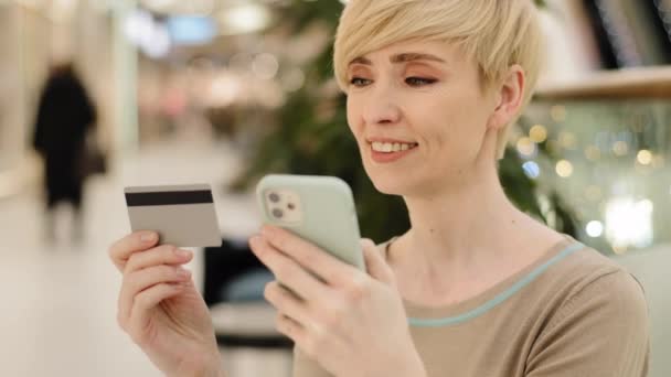 Valkoihoinen keski-ikäinen aikuinen kypsä liiketoiminnan nainen shopper kuluttaja nainen matkapuhelimella ja luottokortilla maksaa tavaroiden online-siirtoja rahaa internet-tilille käyttäen maksu app tekee tilauksen - Materiaali, video