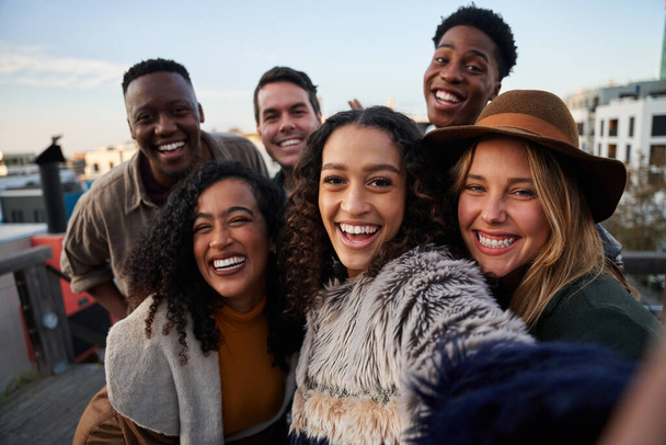 Multikulturelle Freundesgruppe beim Selfie auf einer Party auf dem Dach. Nahaufnahme, Lächeln mit verschiedenen jungen Erwachsenen. - Foto, Bild
