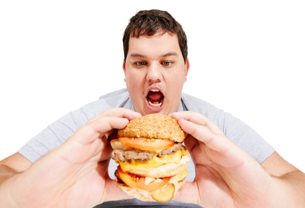 Залезай в мой живот, бургер. Толстый молодой человек собирается съесть огромный гамбургер. - Фото, изображение
