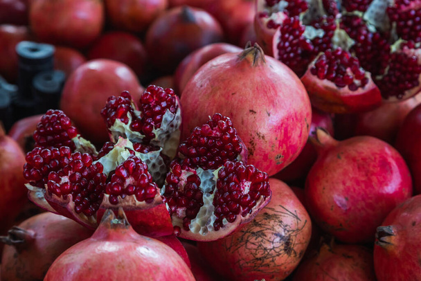 Close-up of bright fruits for background, texture. Red ripe pomegranates on display. - Fotografie, Obrázek
