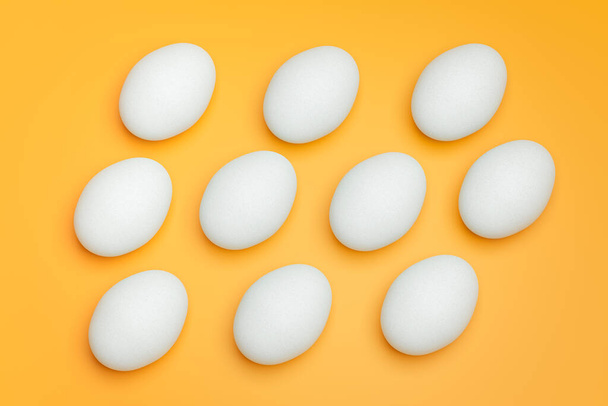 Pattern from white chicken eggs on yellow background top view. Creative food minimalistic background. - Foto, afbeelding