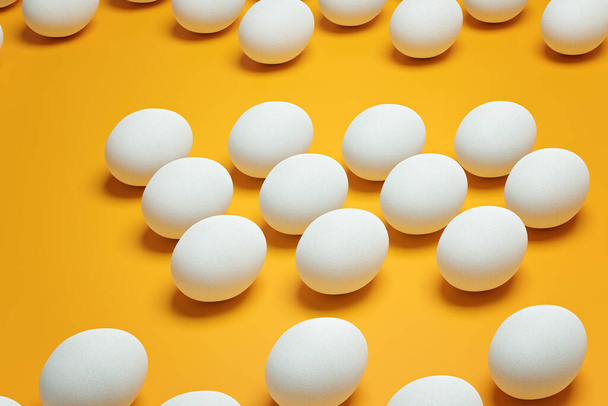 White chicken eggs on yellow background top view. Creative food minimalistic background. - Foto, afbeelding