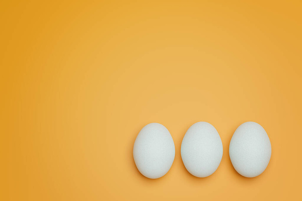 Drei weiße Hühnereier auf gelbem Hintergrund von oben. Kreativer, minimalistischer Hintergrund. - Foto, Bild