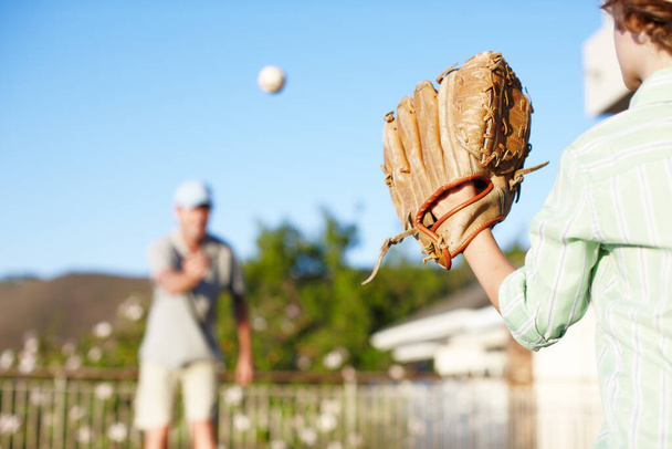 Agarrándose de su guante. Cortado tiro de un padre y un hijo lanzando el béisbol al aire libre en el patio. - Foto, imagen