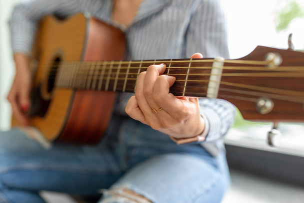 primer plano de la mujer tocando la guitarra sentado en el alféizar - Foto, imagen