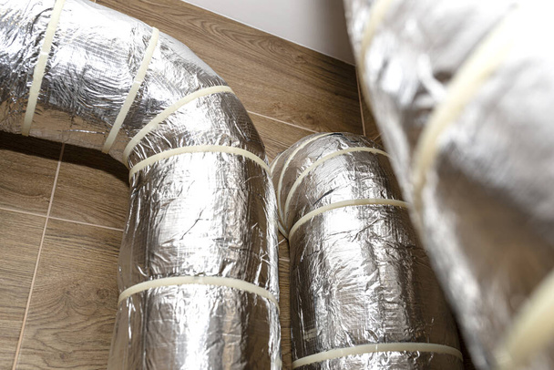 Entrada de aire y escape en el hogar ventilación mecánica con recuperación de calor con tubos aislados visibles con lámina de plata que entra en la pared. - Foto, imagen