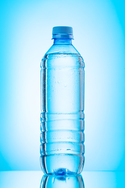 plastic waterfles over blauwe achtergrond - Foto, afbeelding