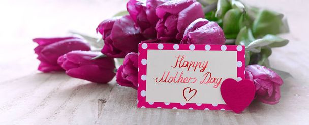 Happy Mothers Day card con tulipani viola su sfondo di legno. - Foto, immagini