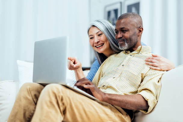 cinematic image of an happy multiethnic senior couple. Indoors Lifestyle moments at home. Concept about seniority and relationships - Foto, Imagem