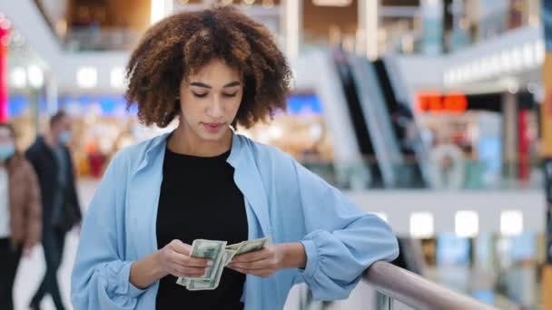 Millennial african american girl shopper consumer client woman standing in shopping business center counting money cash dollars banknotes earning profit salary winning checks finances buying discount - Footage, Video