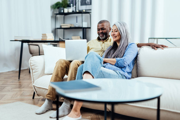 Cinematic image of an happy multiethnic senior couple. Indoors Lifestyle moments at home. Concept about seniority and relationships - Φωτογραφία, εικόνα