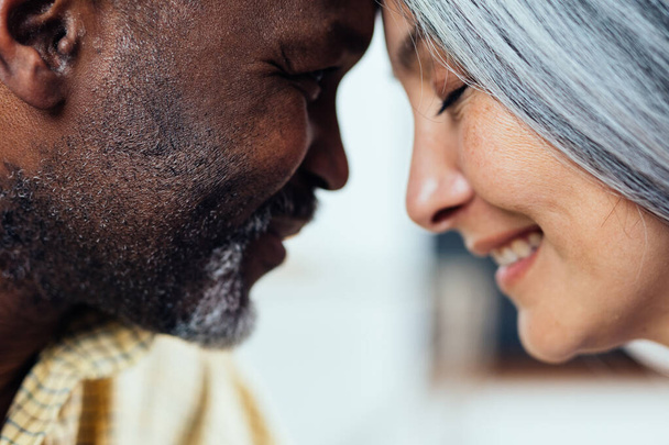 cinematic image of an happy multiethnic senior couple. Indoors Lifestyle moments at home. Concept about seniority and relationships - Photo, Image