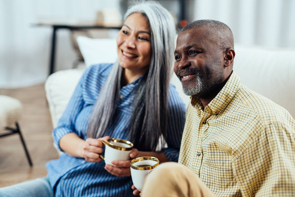 cinematic image of a multiethnic senior couple. Indoors Lifestyle moments at home. Concept about seniority and relationships - Foto, Bild