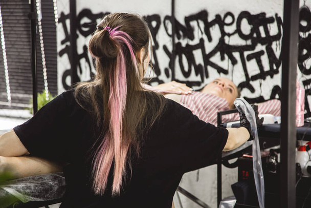 Woman tattoo artist doing tattoo in studio, making tattoo on body. closeup - Valokuva, kuva