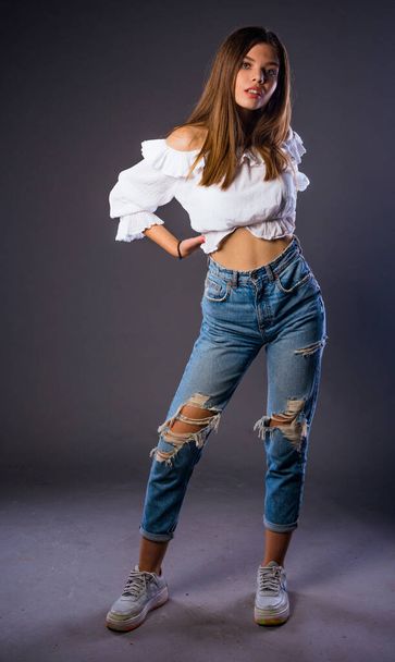 Stijlvol modemeisje poseren in trendy kleding tegen grijze achtergrond - Foto, afbeelding