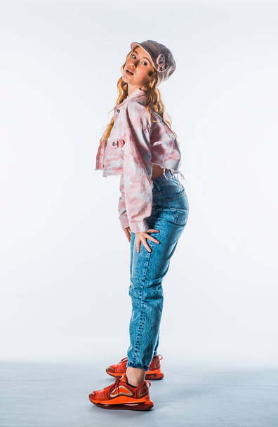 ody shot of a cool modern girl wearing blue jeans, colorful jacket and red sneakers - Фото, изображение