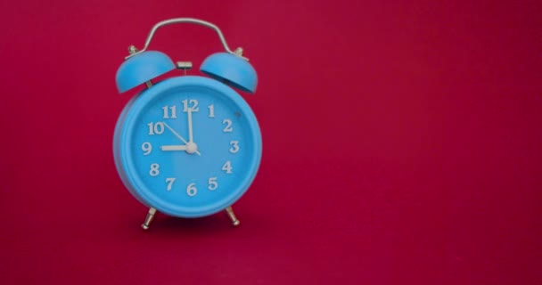 Video con sonido - un despertador azul sobre un fondo rojo suena a las 9 AM - Imágenes, Vídeo
