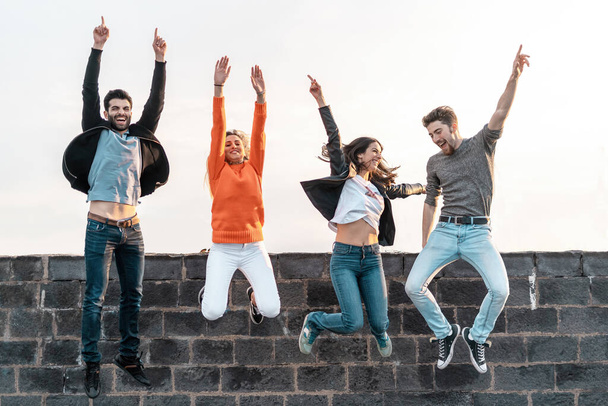 Iloisia hauskoja ystäviä nauttimassa elämästä hyppäämällä lähellä substantiivin seinää Huolettoman nuoren käsite hauskaa viikonloppuna lomalla - Valokuva, kuva