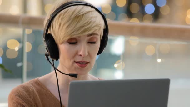 Front view head shot middle aged adult 40s woman in headset microphone looking at web camera on laptop female online teacher coach psychologist helpline agent tutor giving video call educational class - Footage, Video