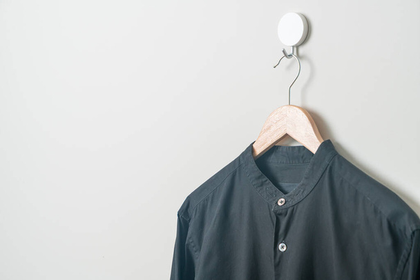 chemise noire suspendue avec cintre en bois sur le mur - Photo, image