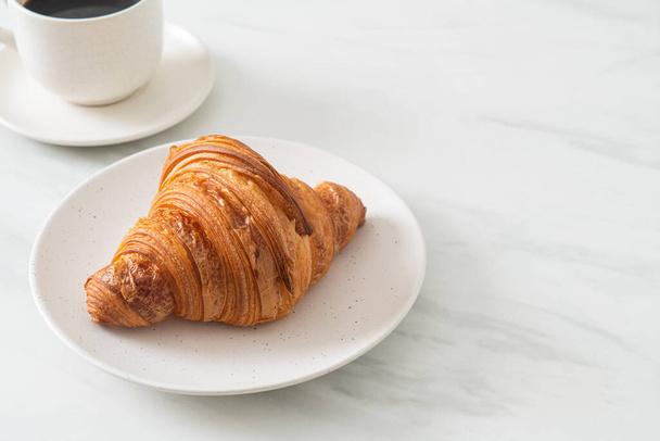fresh croissant on white plate with black coffee - Photo, image