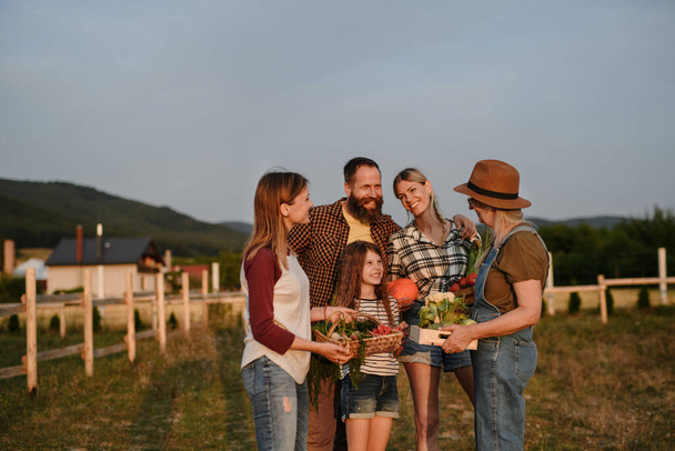 Happy farmer family holding their harvest outdoors in garden. - Φωτογραφία, εικόνα