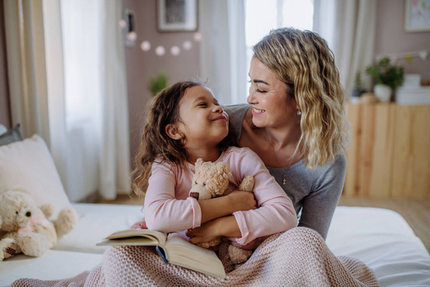 Happy mother hodling her little daughter and looking at each other in bed. - Foto, immagini