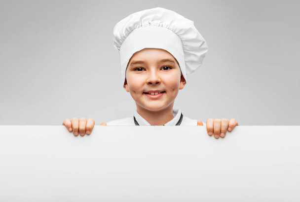 happy little boy in chefs toque with white board - Foto, afbeelding