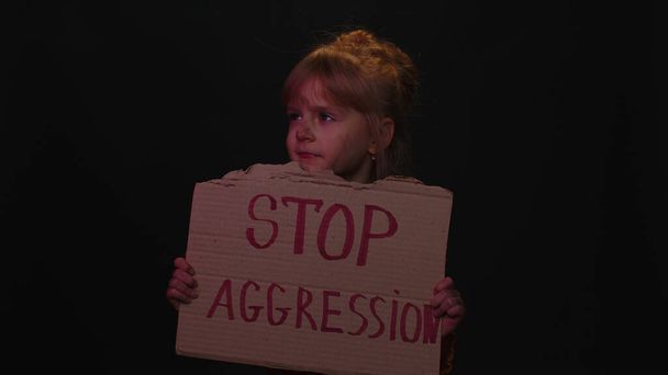 KYIV, UCRANIA - 24 de febrero de 2022: Niño sin hogar con miedo levanta el masaje de inscripción Stop Aggression - Foto, imagen