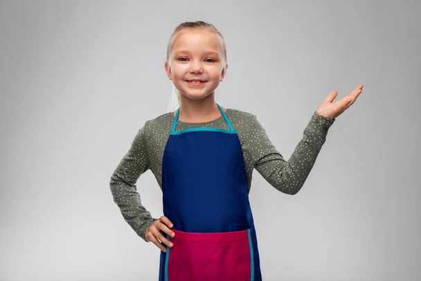 little girl in apron holding something on hand - Фото, изображение