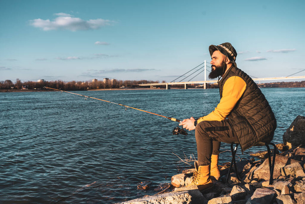 Man enjoys fishing by a river. - Photo, Image