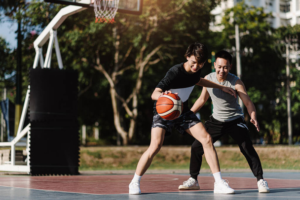 Концепция спорта и отдыха двух баскетболистов, играющих вместе в баскетбол на спортивной площадке. - Фото, изображение