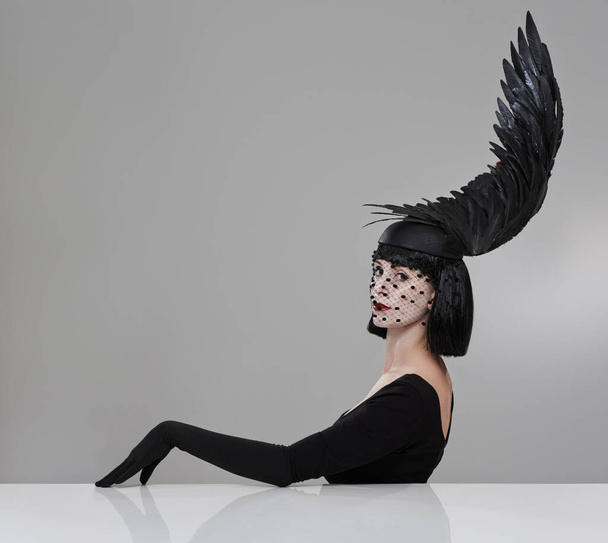Just winging it. Shot of a young woman in a wing-shaped headpiece sitting in a studio. - Zdjęcie, obraz