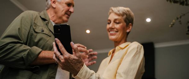 Caucasian senior couple texting on cellular device - Fotó, kép