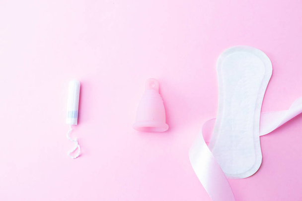 Kubek menstruacyjny, tampon, kobiecy kubek dla ochrony sanitarnej. Różowa wstążka z kubkiem menstruacyjnym. Okres menstruacji kobiecej. Koncepcja zerowej ilości odpadów, ekologiczny styl życia, mniejsze zużycie banerów - Zdjęcie, obraz